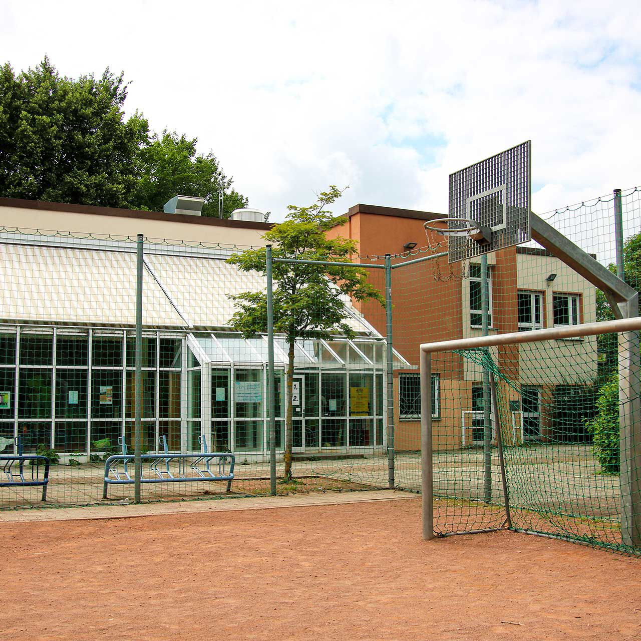 Der Außenbereich des Jugendhaus Compact mit einem Bolzplatz im Vordergrund und im Hintergrund das Hauptgebäude.