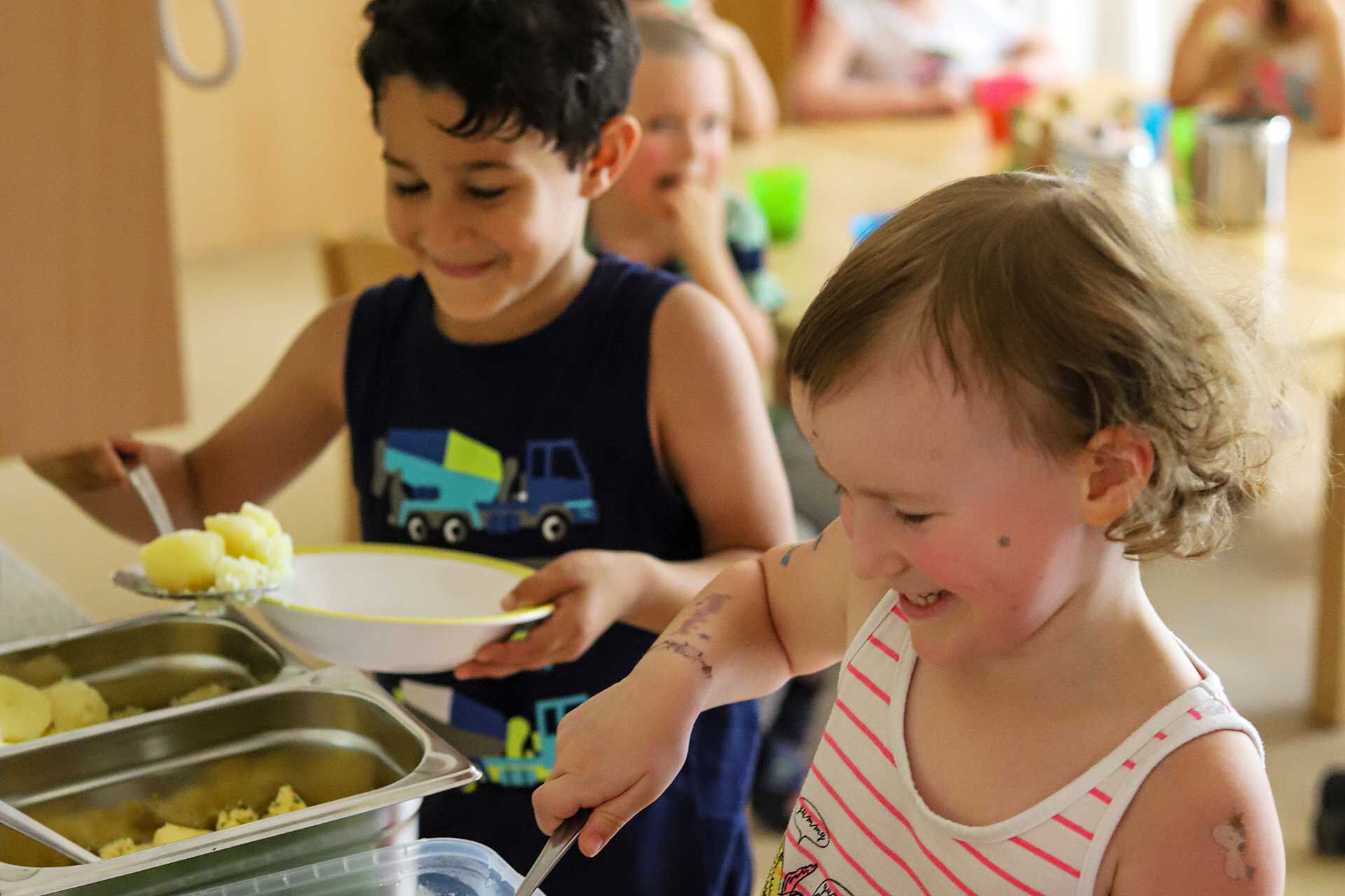 Das Mittagessen wird sich von den Kindern selbst auf den Tellern getan. Es gibt Kartoffeln, Spinat und Ei.