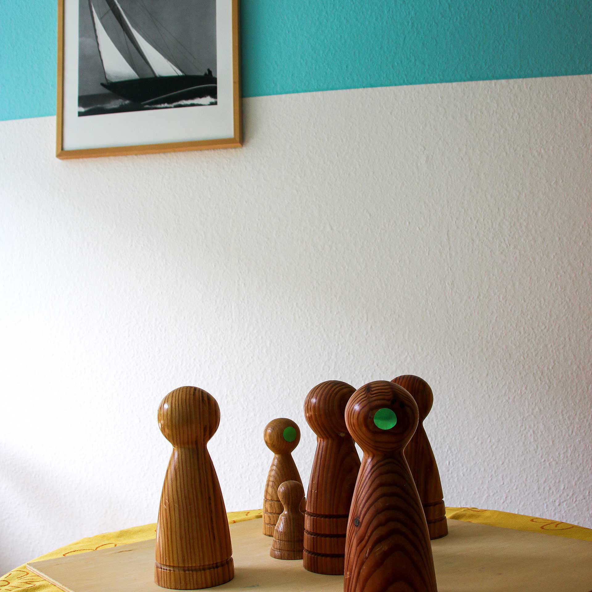 6 Holzfiguren zur Personenaufstellung stehen auf einem Holzbrett auf dem Tisch.
