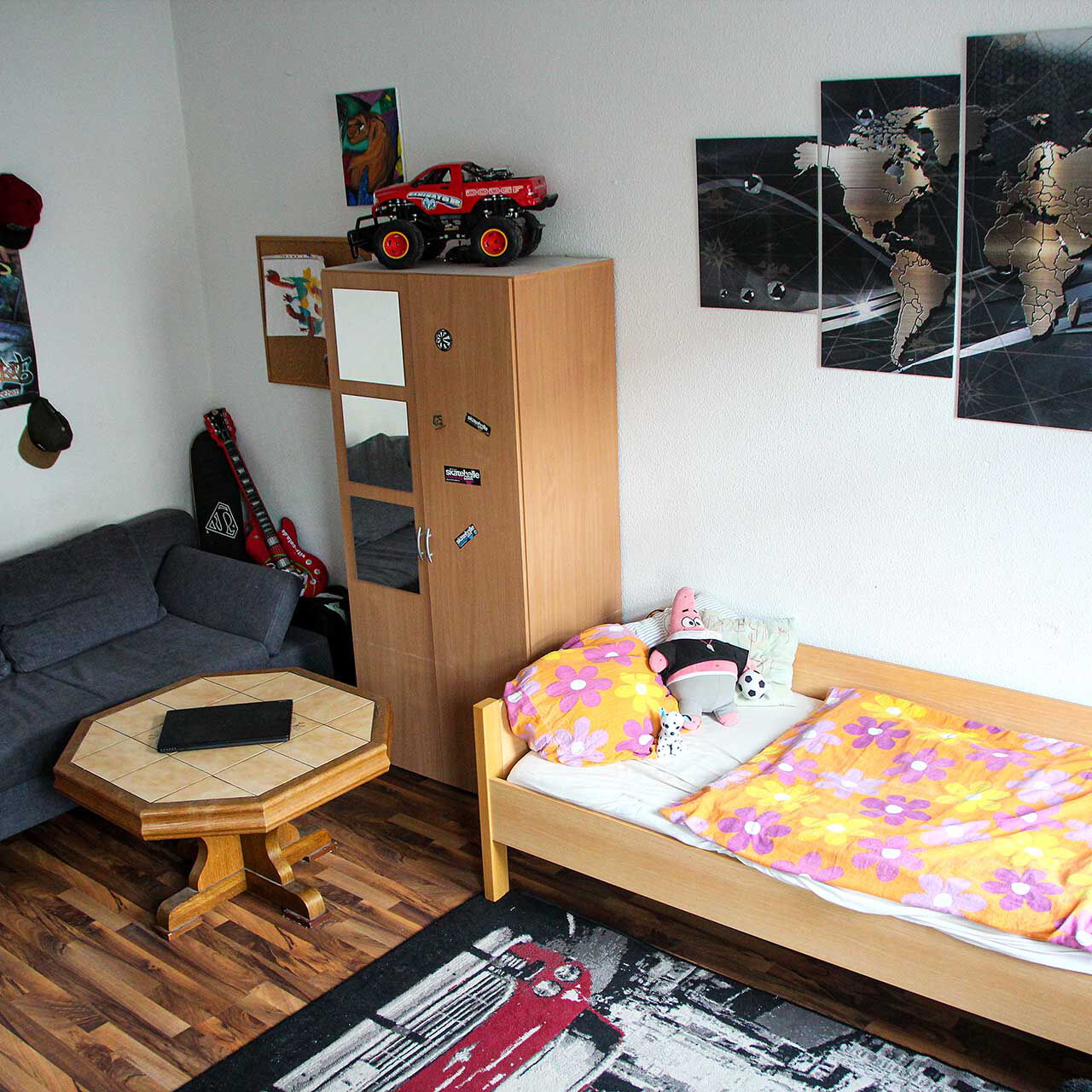 Ein Jugendzimmer mit Sofa, Bett, Sofatisch und Schrank.