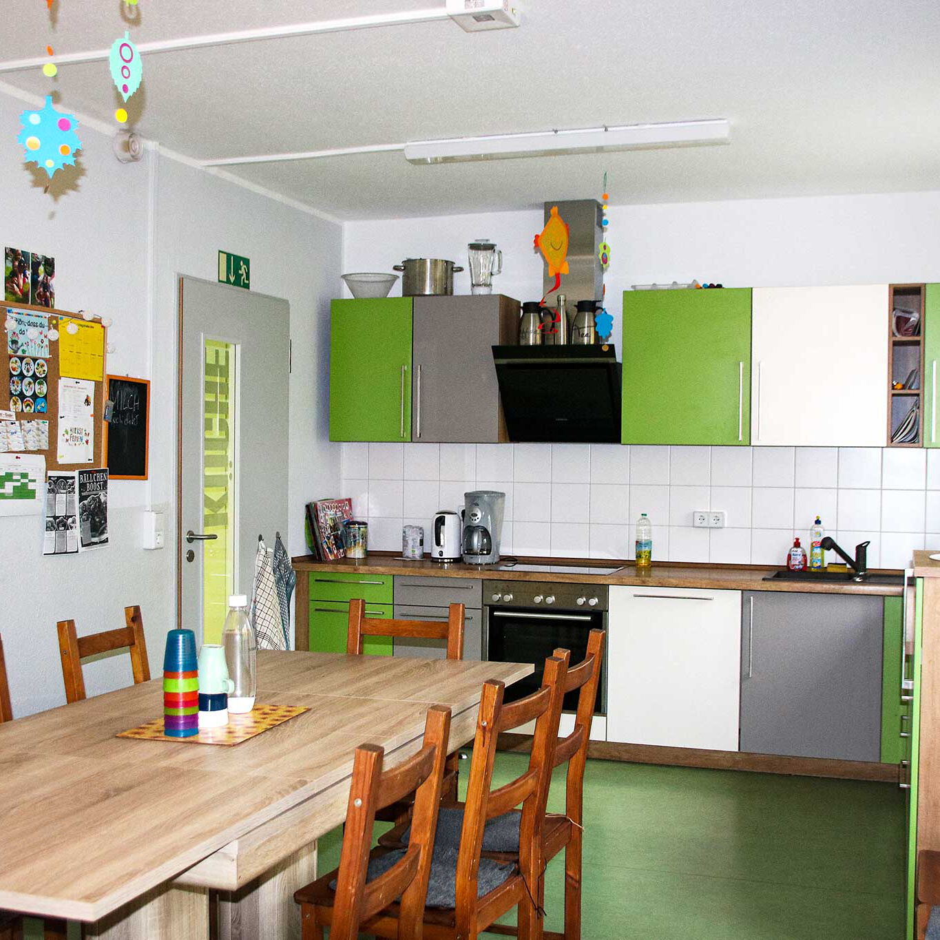 Eine grün weiße Wohnküche mit einem großen Esstisch und 8 Stühlen.