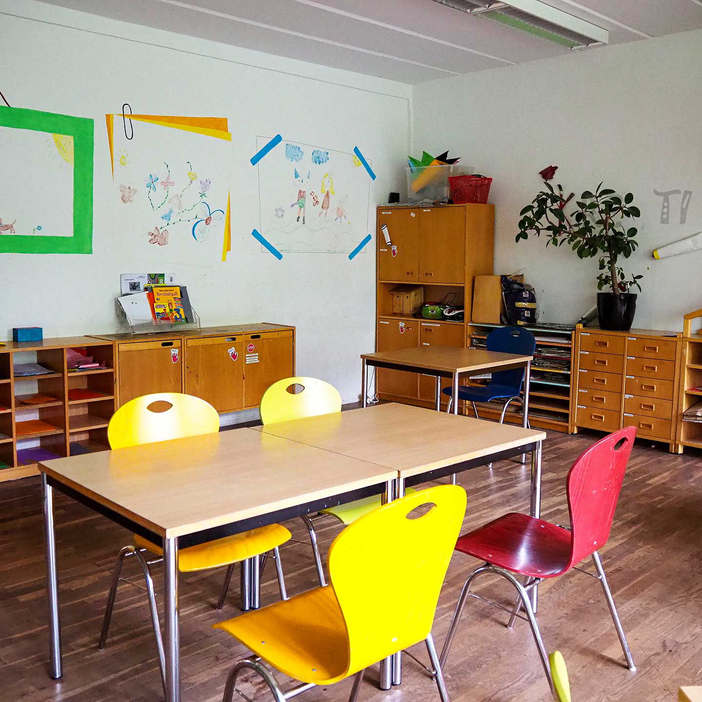 Im Hausaufgabenzimmer stehen drei Tische und fünf Stühle für die Erledigung der Hausaufgaben zur Verfügung. An der Wänden stehen Anbauwände für Schulmaterialien.