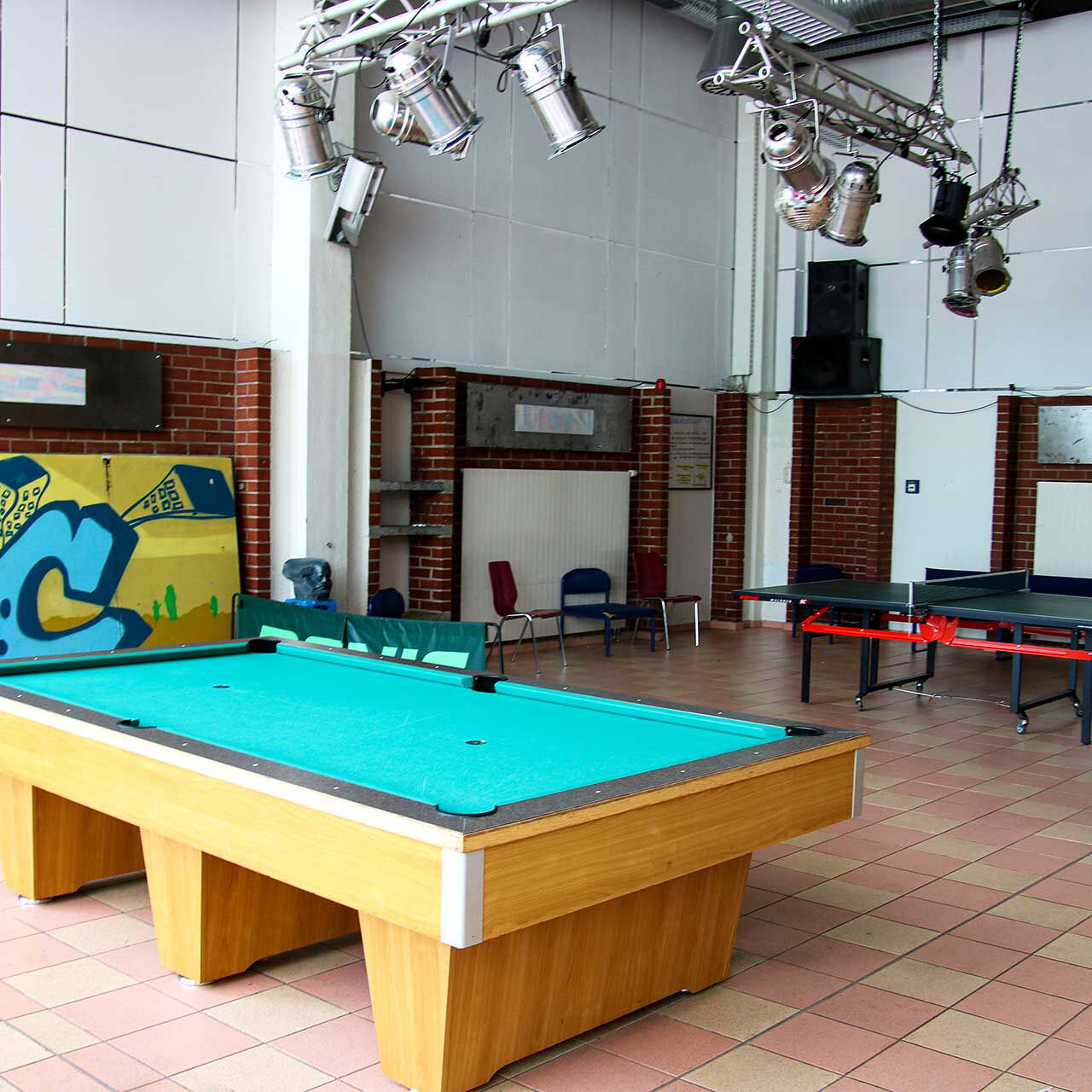 In der Spielhalle ist der Billardtisch im Vordergrund und die Tischtennisplatte im Hintergrund zu sehen.