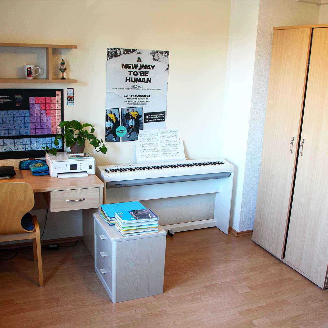 Im Einzelzimmer steht ein Schreibtisch und Klavier an der Wand. In der Ecke steht ein Kleiderschrank.