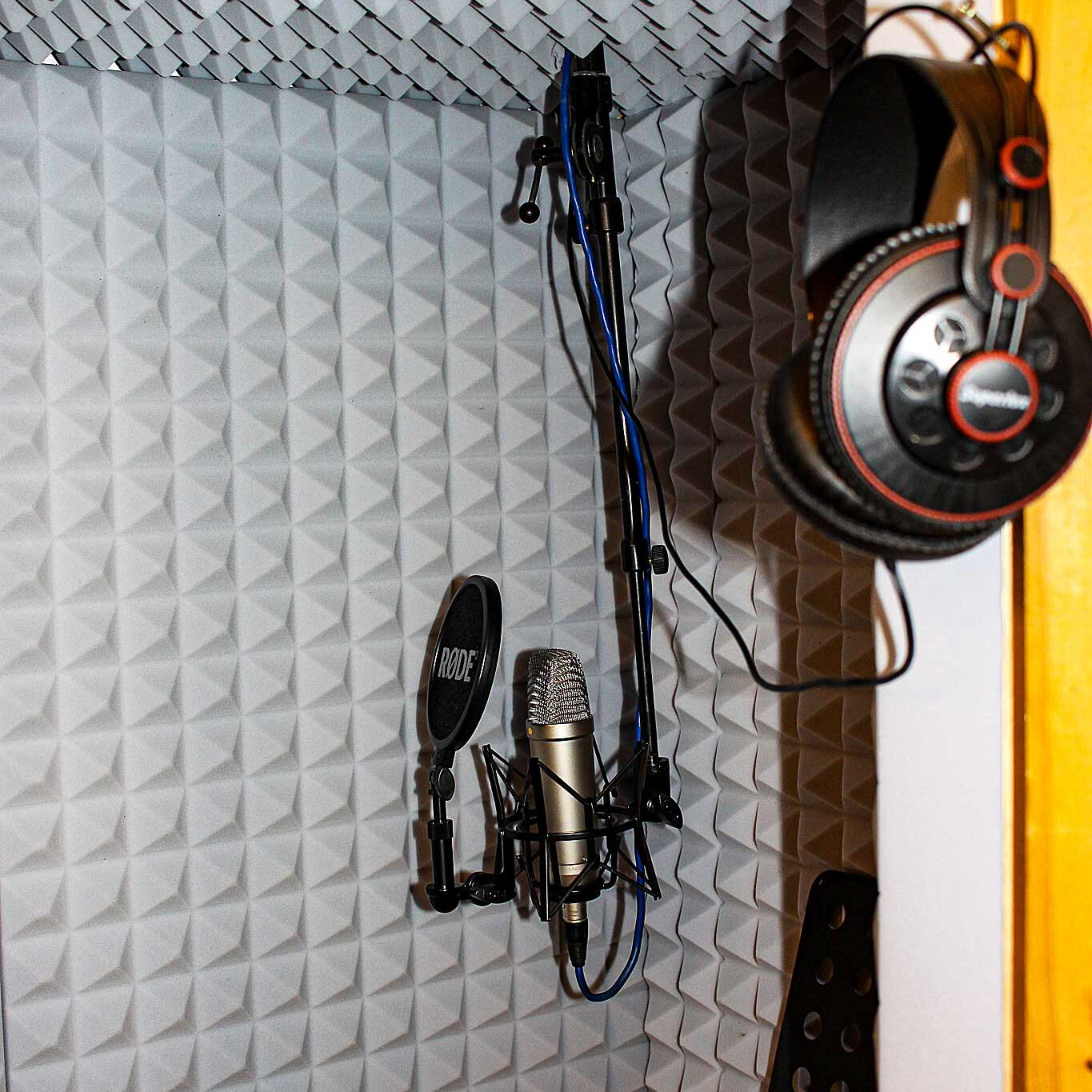 Ein Mikrofon, Kopfhörer und ein Notenständer in einem schallisolierten Raum.