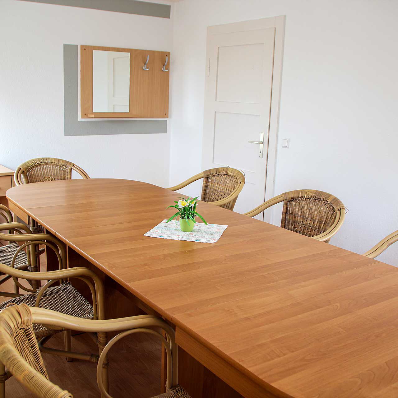 Ein Beratungsraum mit acht Stühlen und einem langen Holztisch.