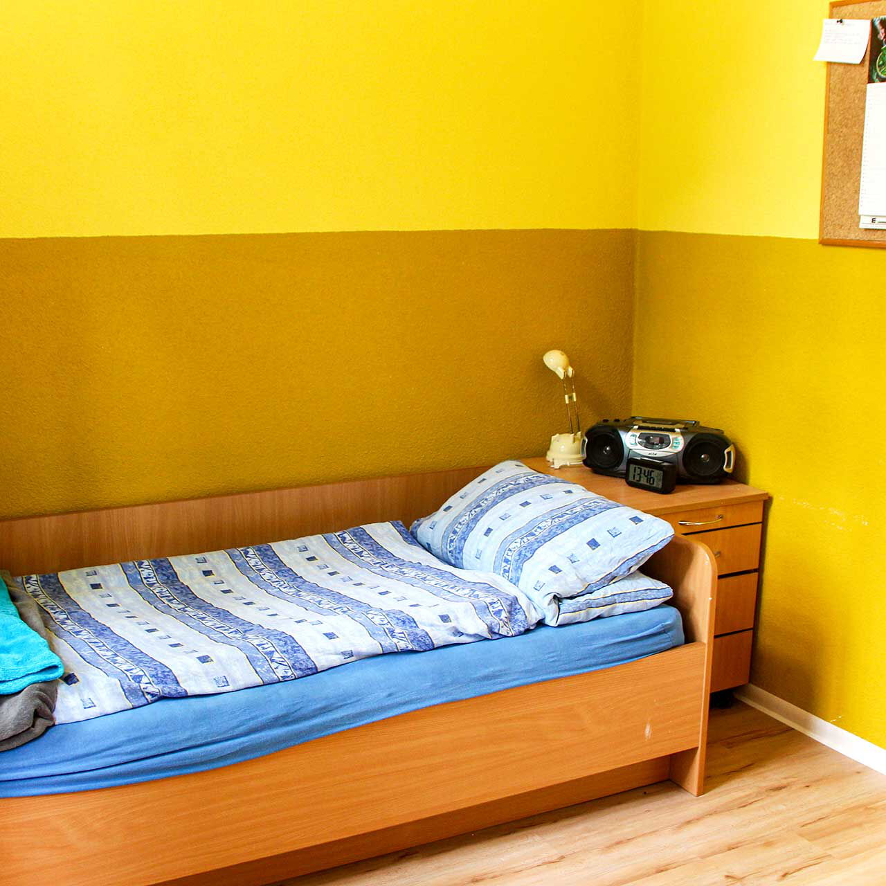 Ein Einzelzimmer mit einem Bett und Nachttischschrank.