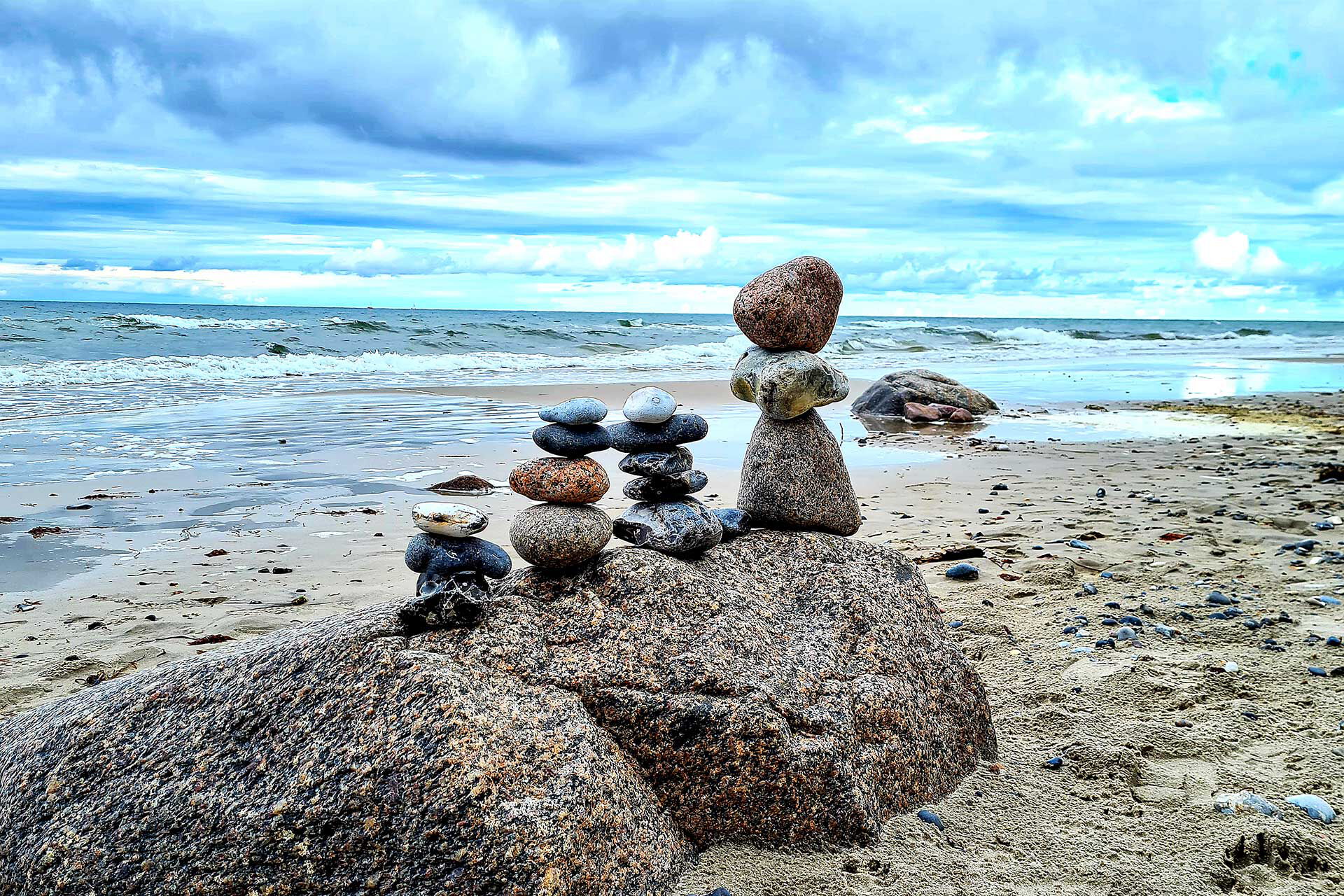 4 Steintürme stehen auf einem Felsen am Strand.