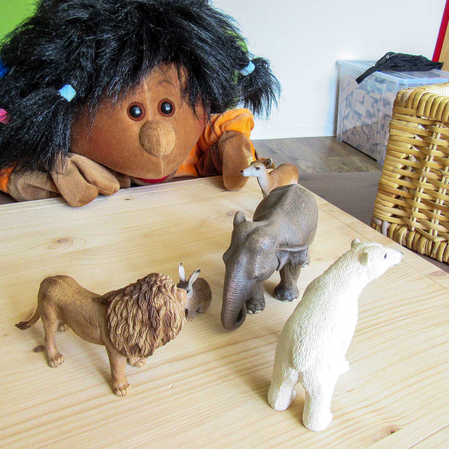 Auf einem Holztisch stehen ein Hase, Reh, Elefant, Löwe und Eisbär.