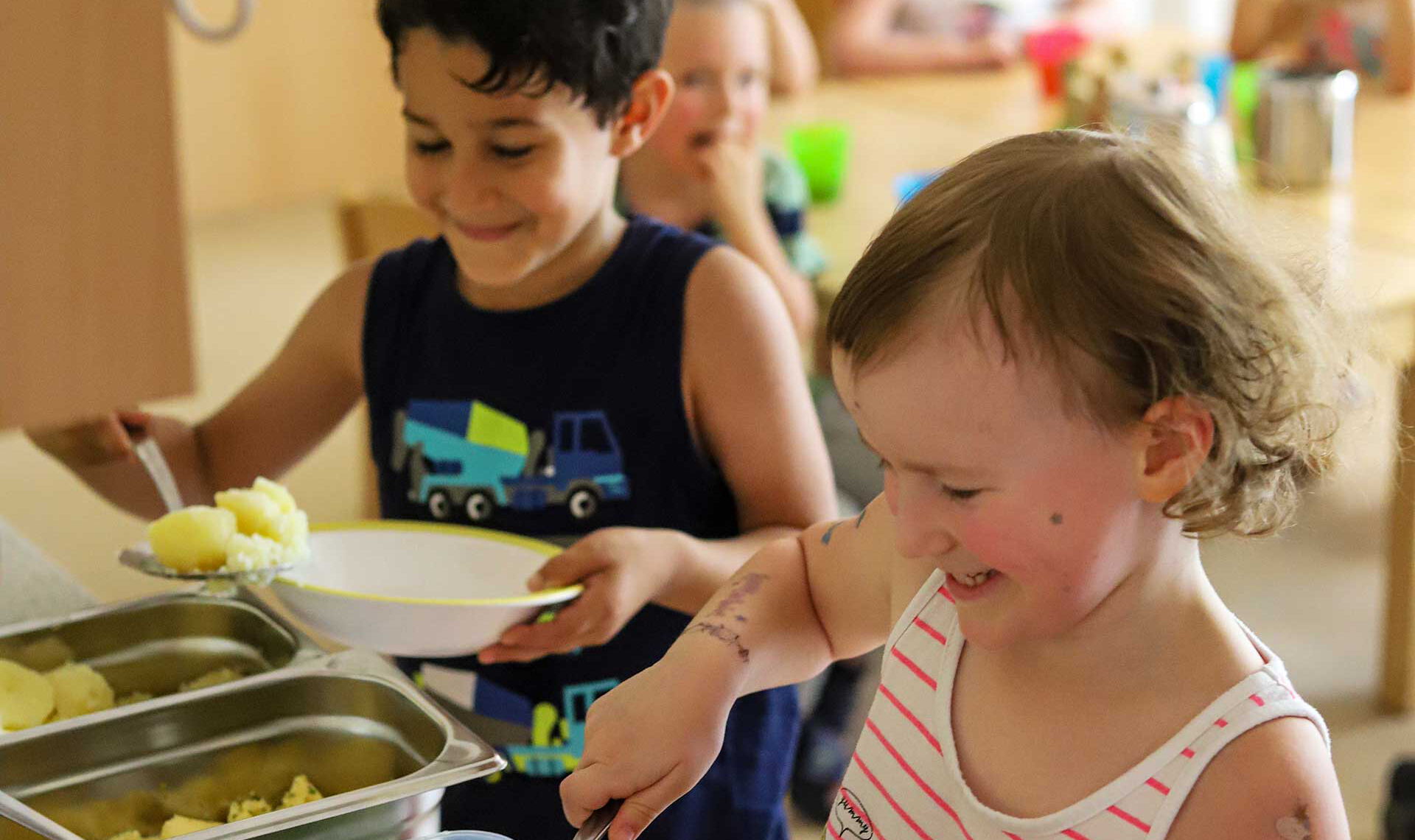 Das Mittagessen wird sich von den Kindern selbst auf den Tellern getan. Es gibt Kartoffeln, Spinat und Ei.