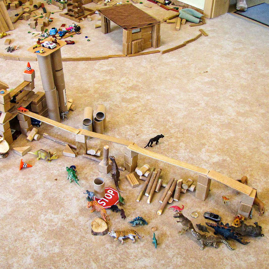 Das Bauzimmer mit vielen Holzbausteinen und Spielfiguren auf einem gemütlichen Teppichboden.
