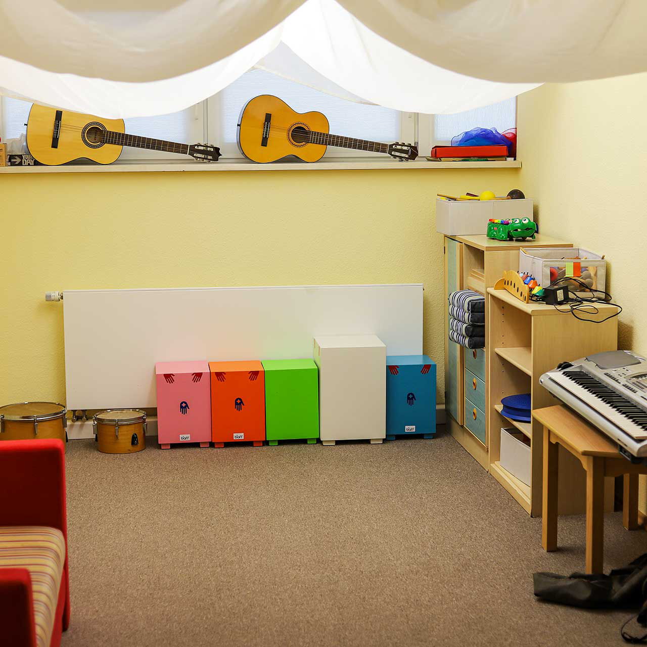 Im Musikzimmer stehen unterschiedliche Musikinstrumente (Gitarre, Keyboard, Trommeln, Rasseln) für die Kinder bereit.