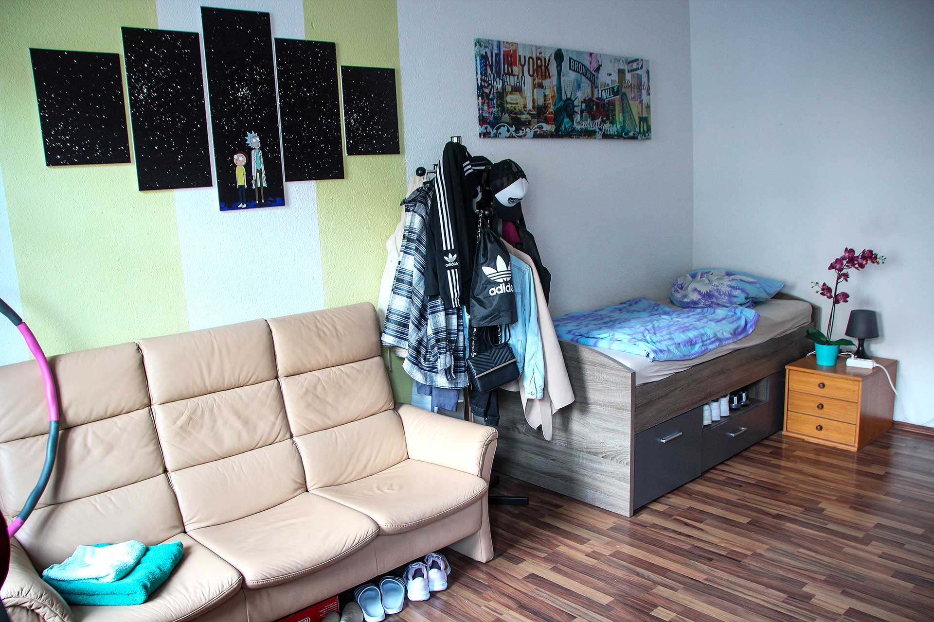 Ein Jugendzimmer mit einem Ledersofa, Bett und einer Garderobe.